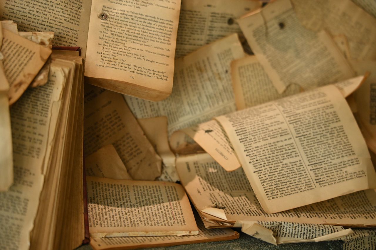 A collection of aged, open books with partially torn pages create a nostalgic atmosphere.